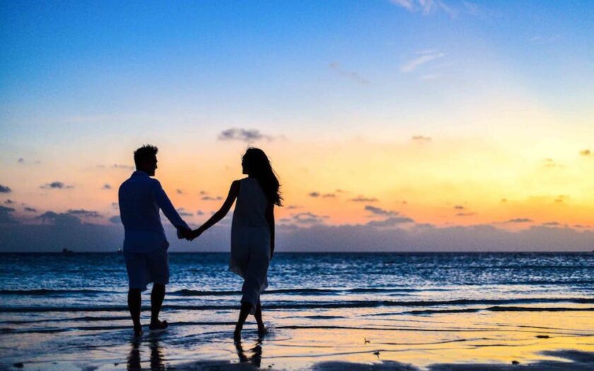 Îndrăgostiți care țin de mână seara pe plajă