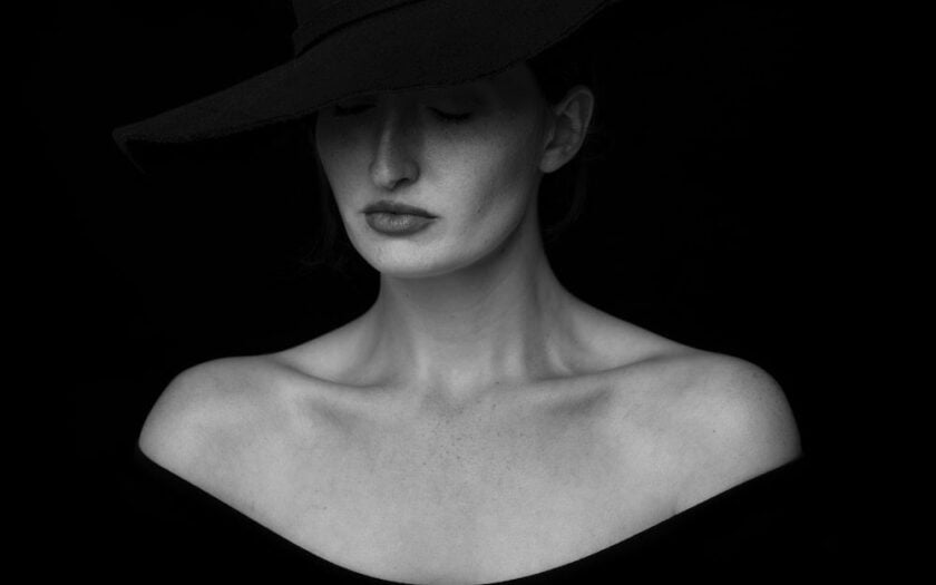 Femeie cu pălărie în întuneric