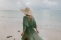 Femeie în rochie verde se plimbă pe plajă