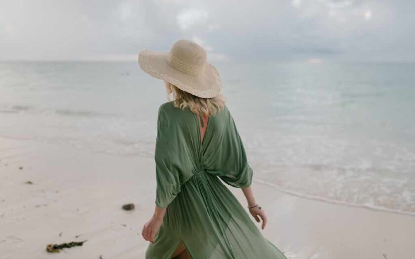Femeie în rochie verde se plimbă pe plajă