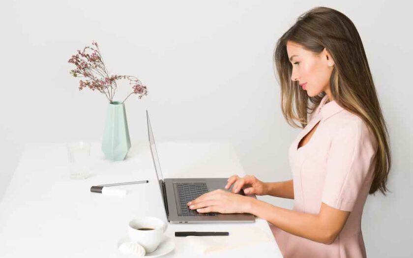 Femeie în rochie roz stă pe laptop